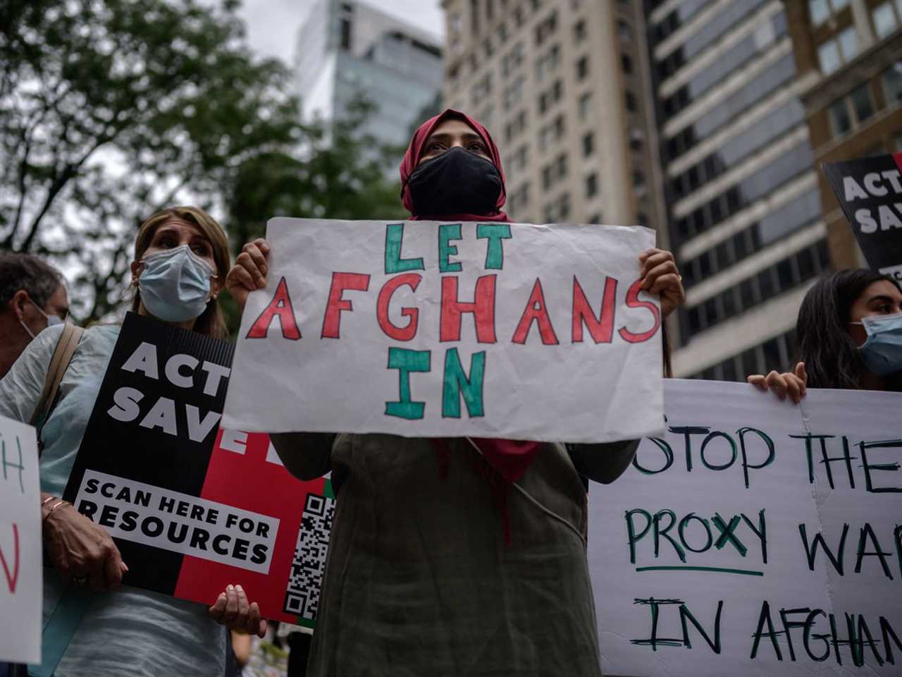 A protester holds a sign that reads, “Let Afghans in.”