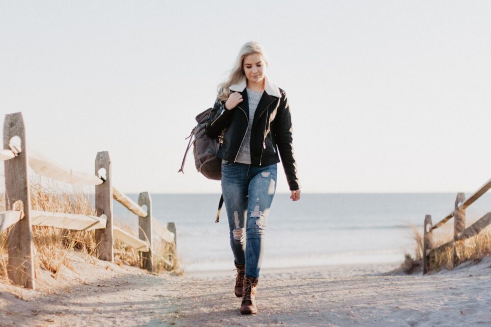 woman carrying a backpack walking on the beach