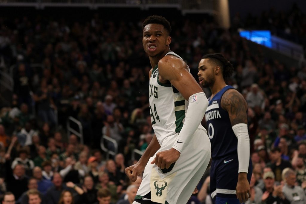 Giannis Antetokounmpo of the Milwaukee Bucks reacts to a dunk in a game against Anthony Edwards and the Minnesota Timberwolves.