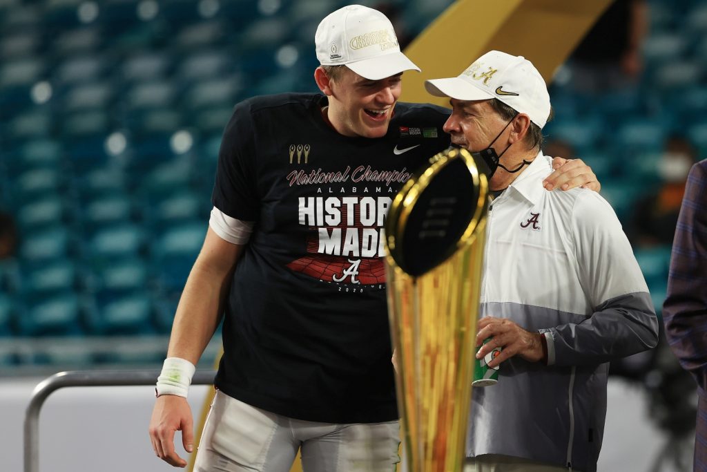 Mac Jones stands with Nick Saban on stage after Alabama's national championship victory.