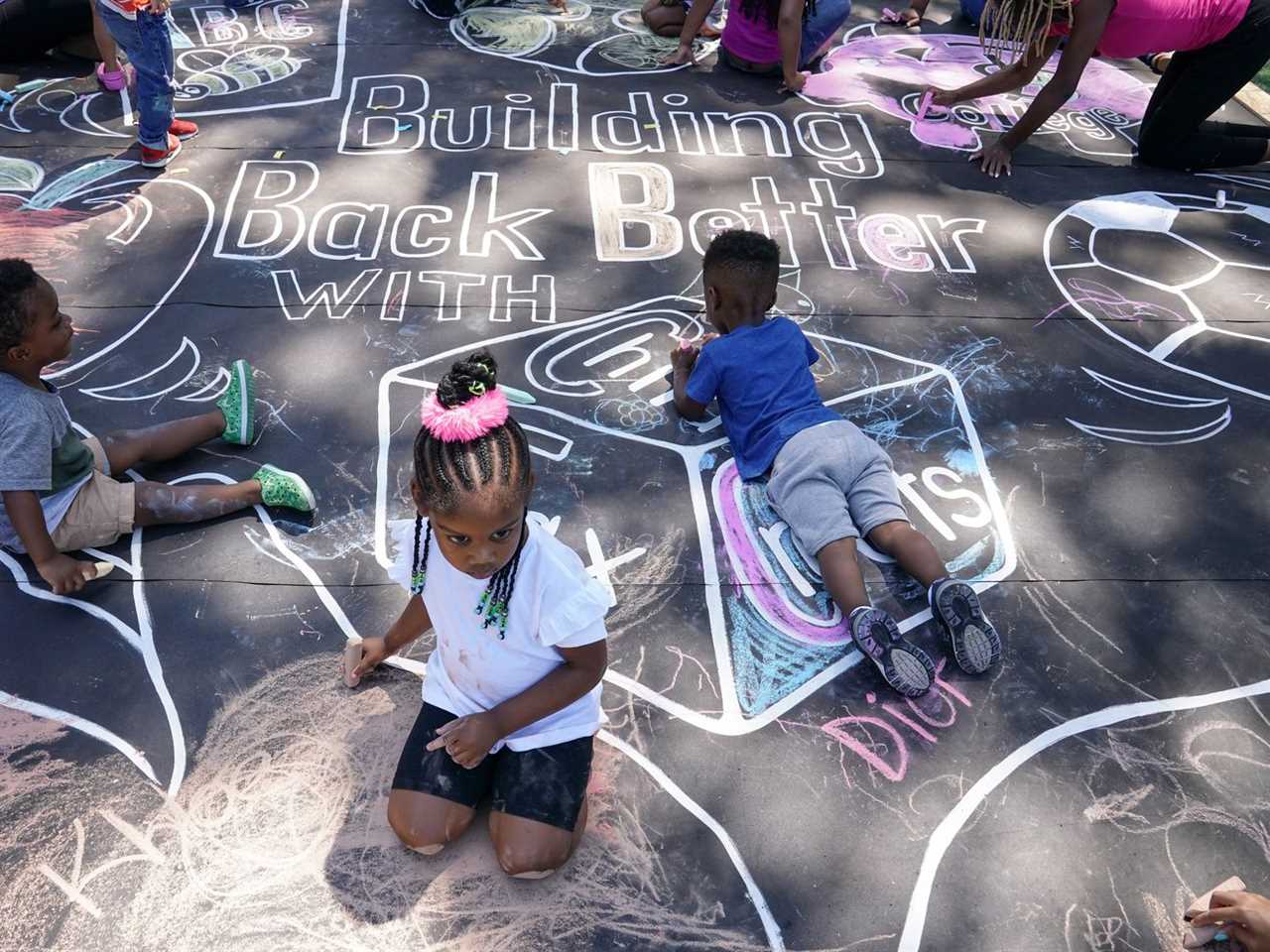 Children draw a chalk mural on a blacktop playground surface.