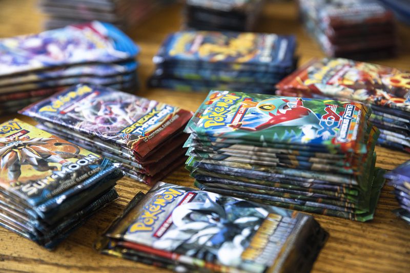 Photo shows stacks of sealed Pokemon cards in their packages.