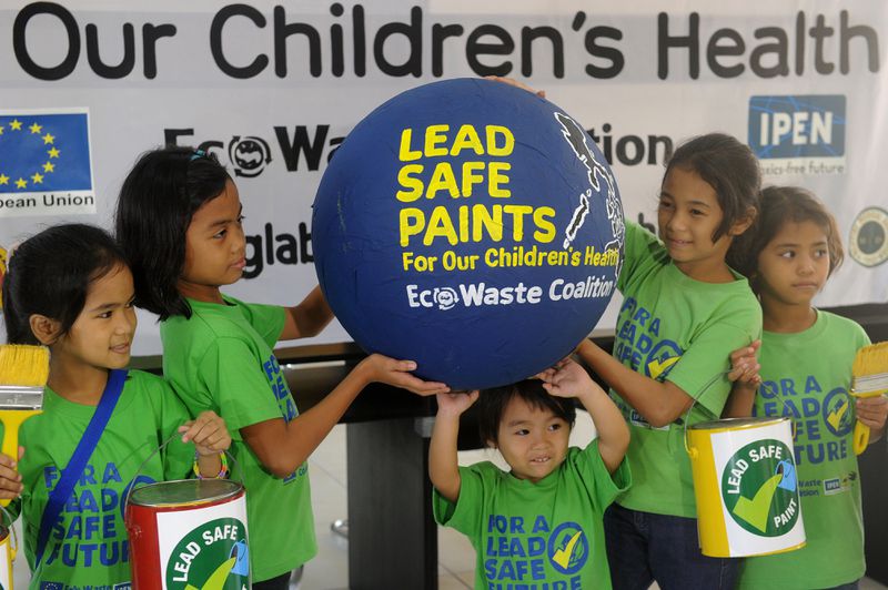 A group of children wearing shirts that read “For a lead safe future” hold up a large ball that reads “Lead safe paints for our children’s health, Eco Waste Coalition.”