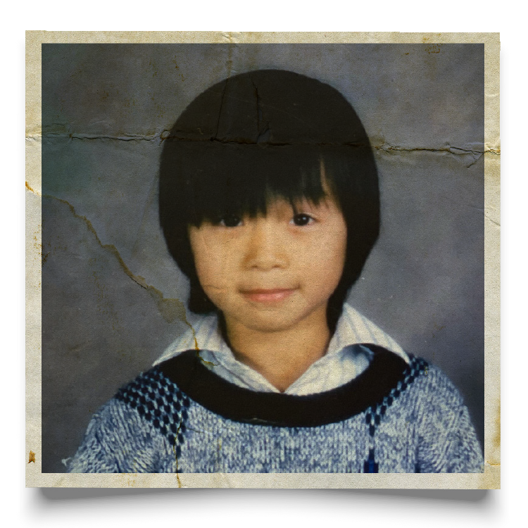 A young Asian American boy in a 1980s-vintage school photo, wearing a collared shirt and patterned sweater.