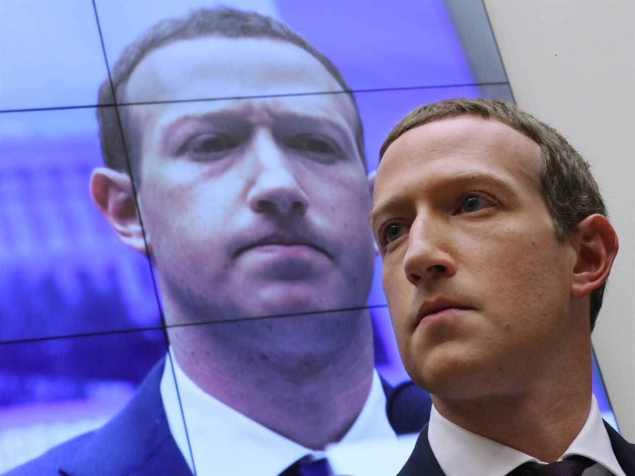 Mark Zuckerberg’s face appearing on a screen behind him.