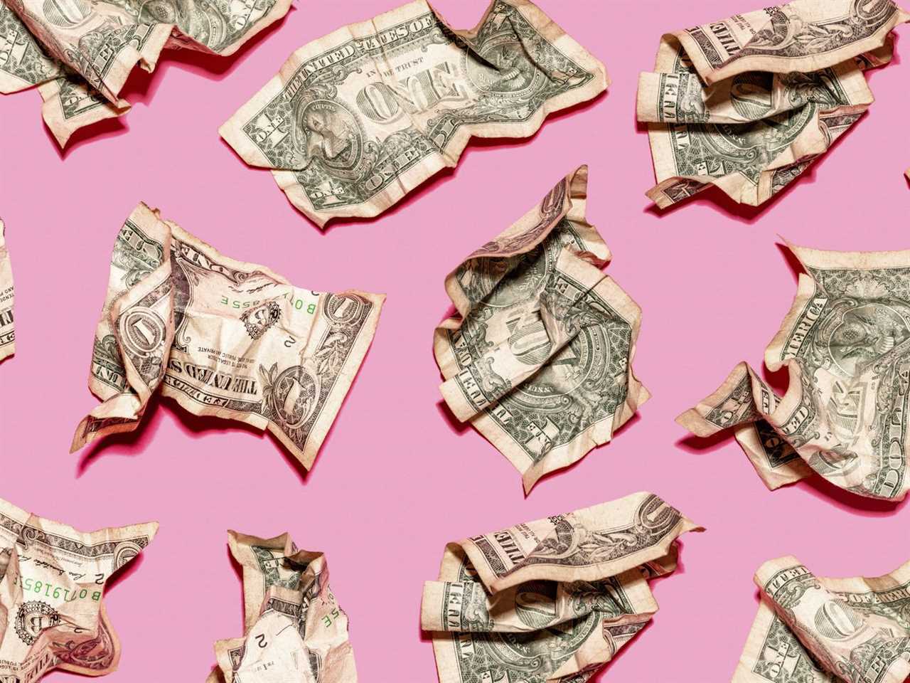 Crumpled dollar bills on a pink background