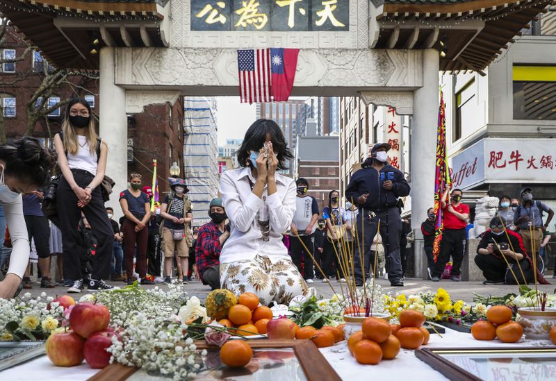 Fiona Phie, head in her hands, kneels in front of offerings of flowers, candles, and incense.