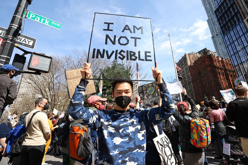 A demonstrator holds a sign reading “I am not invisible.” Behind him more demonstrators hold signs.