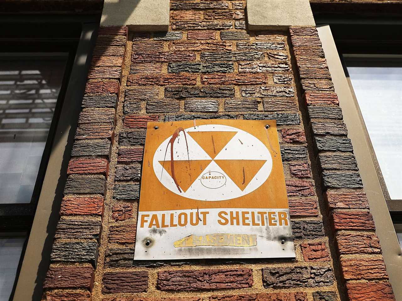 A fallout shelter sign with the three-triangle nuclear symbol, on a brick wall in New York City.