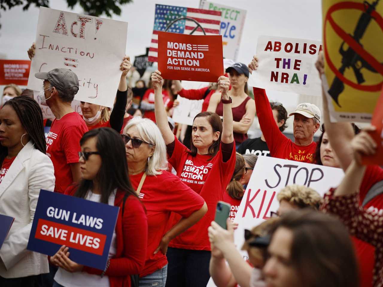 Protesters hold signs that read “Abolish the NRA” and “Gun laws save lives,” among others.