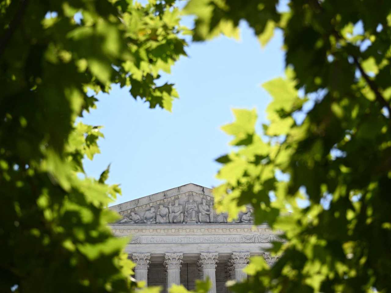 The Supreme Court building is pictured through a gap in the leaves of nearby trees