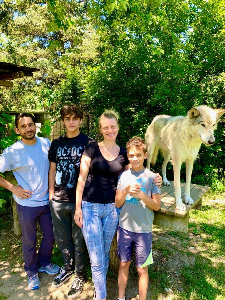 a family standing next to a wolf at howling wood farm