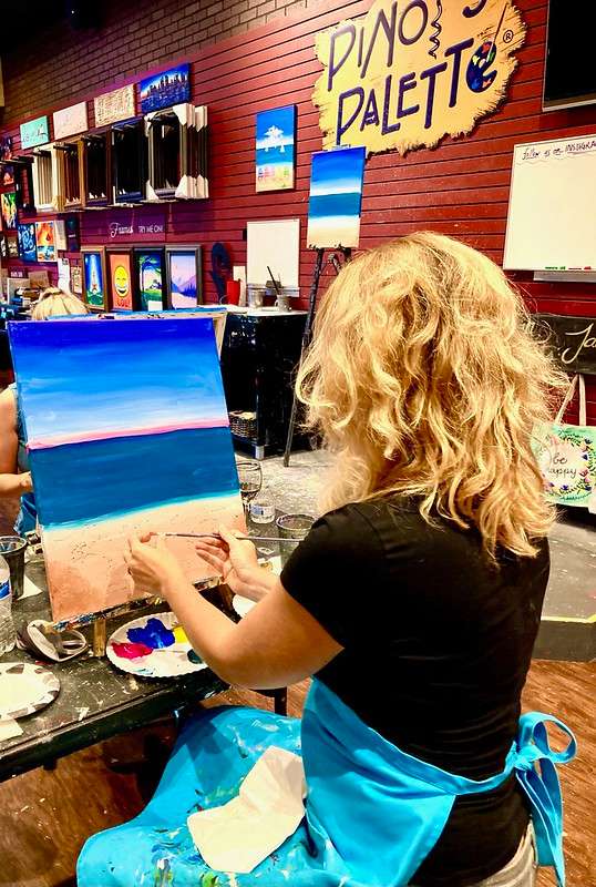 blonde woman painting in a class