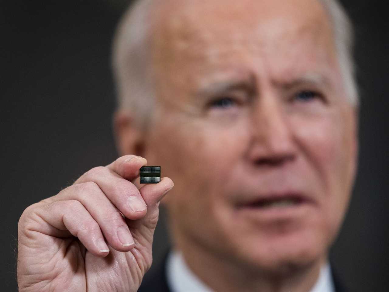 President Joe Biden holds up a semiconductor chip while speaking.