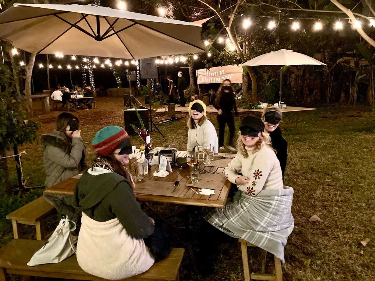 people sitting around a table while blindfolded in a dining in the dark experience