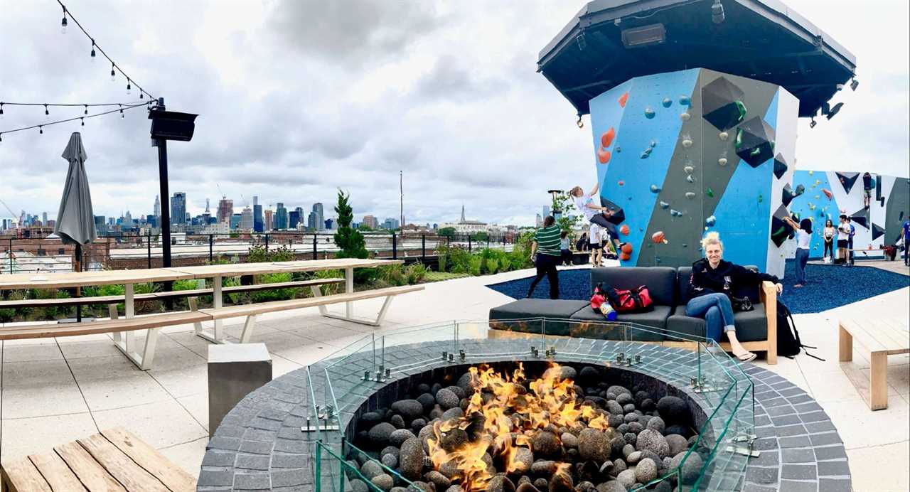 woman sitting behind a fire pit at outdoo vital climbing gym