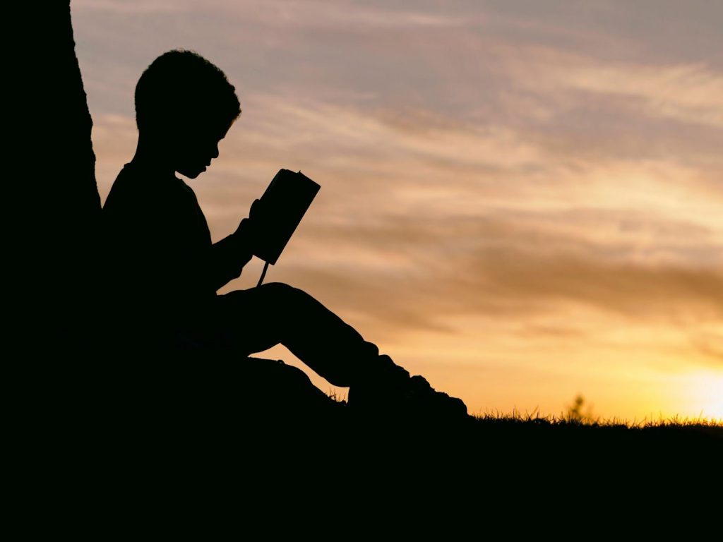 kid reading a book in the sunset