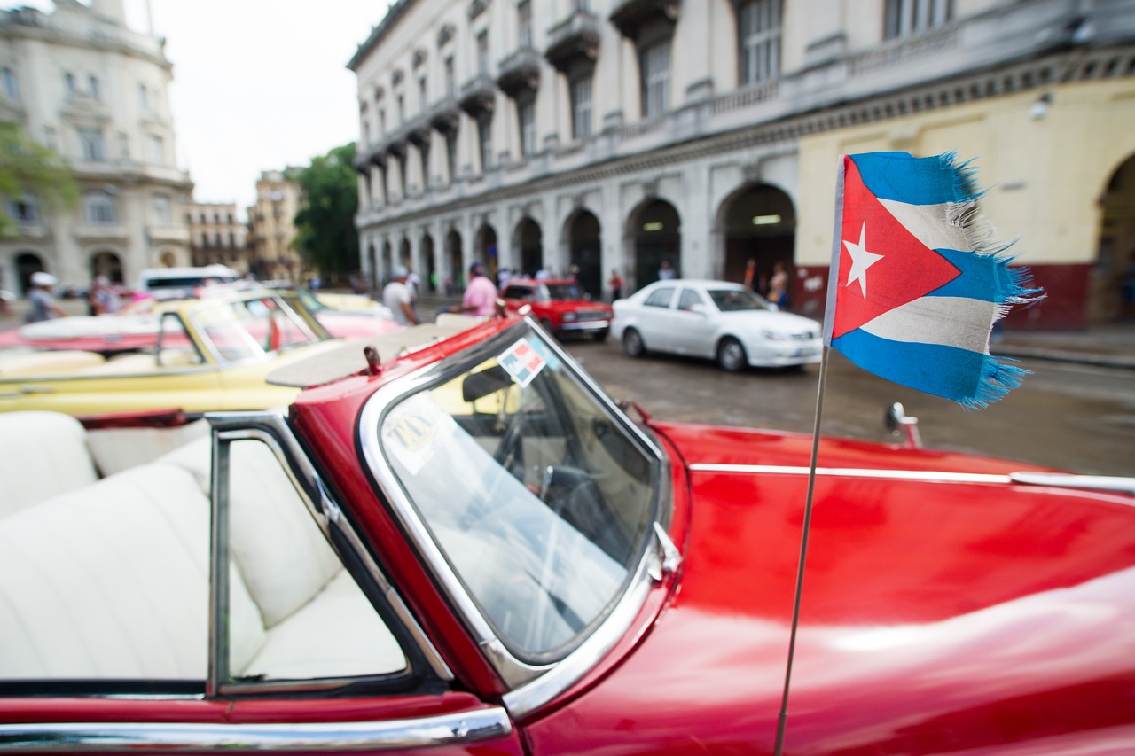 a red old car with the cuban flag in cuba