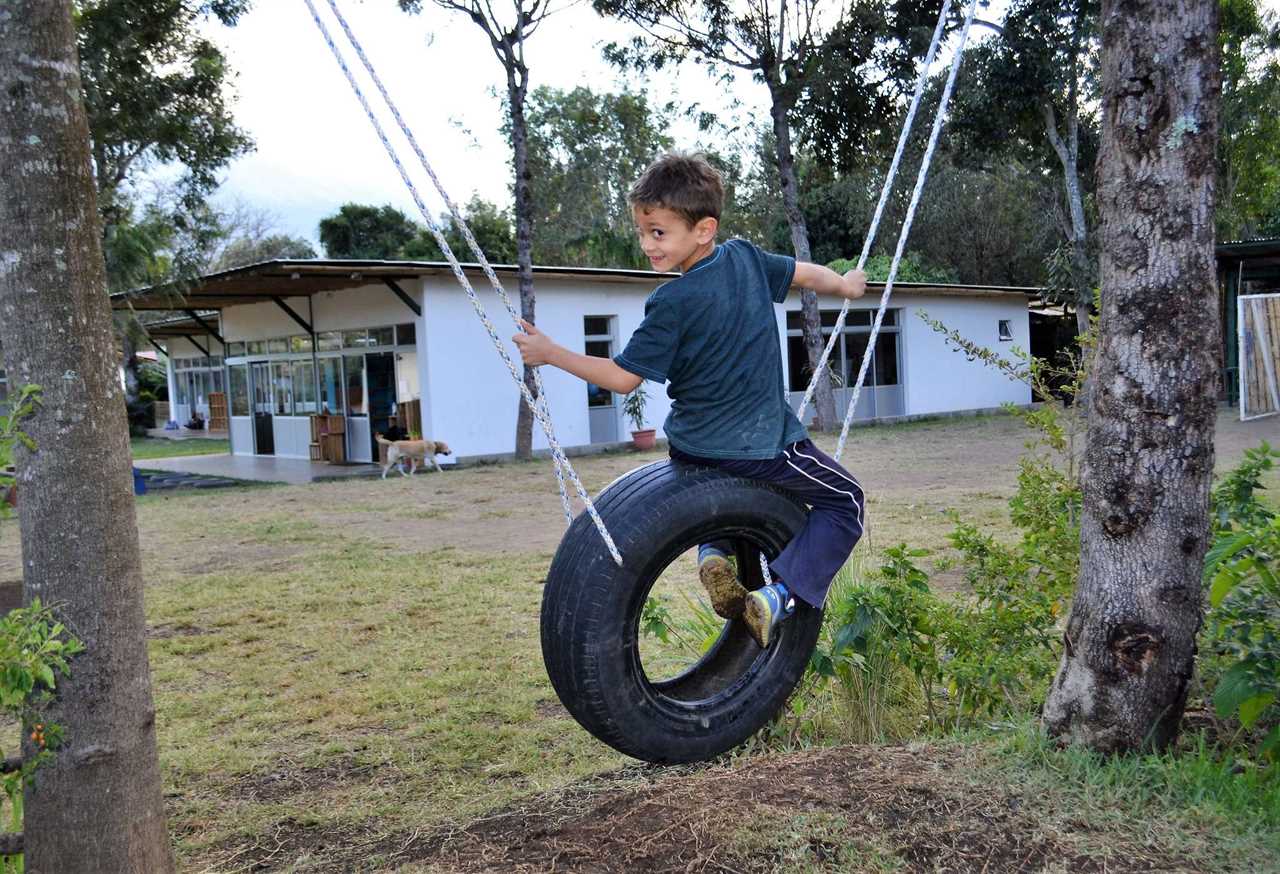 kid on hanging tire at green school in antigua guatemala