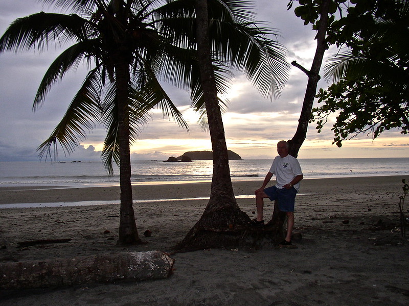 man stading next to a tree and palm tree in Manuel Antonio