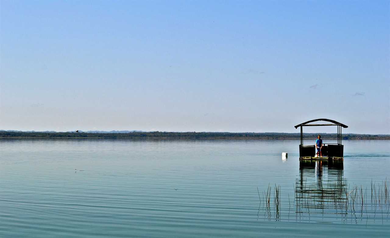 a kid on a floating platform in a river in peten guatemala