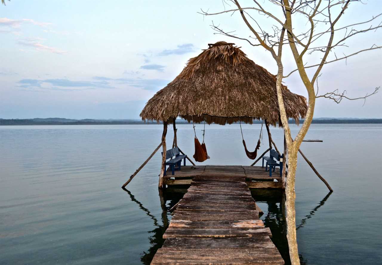 a wooden dock and some hamocks in a river at tikal national park