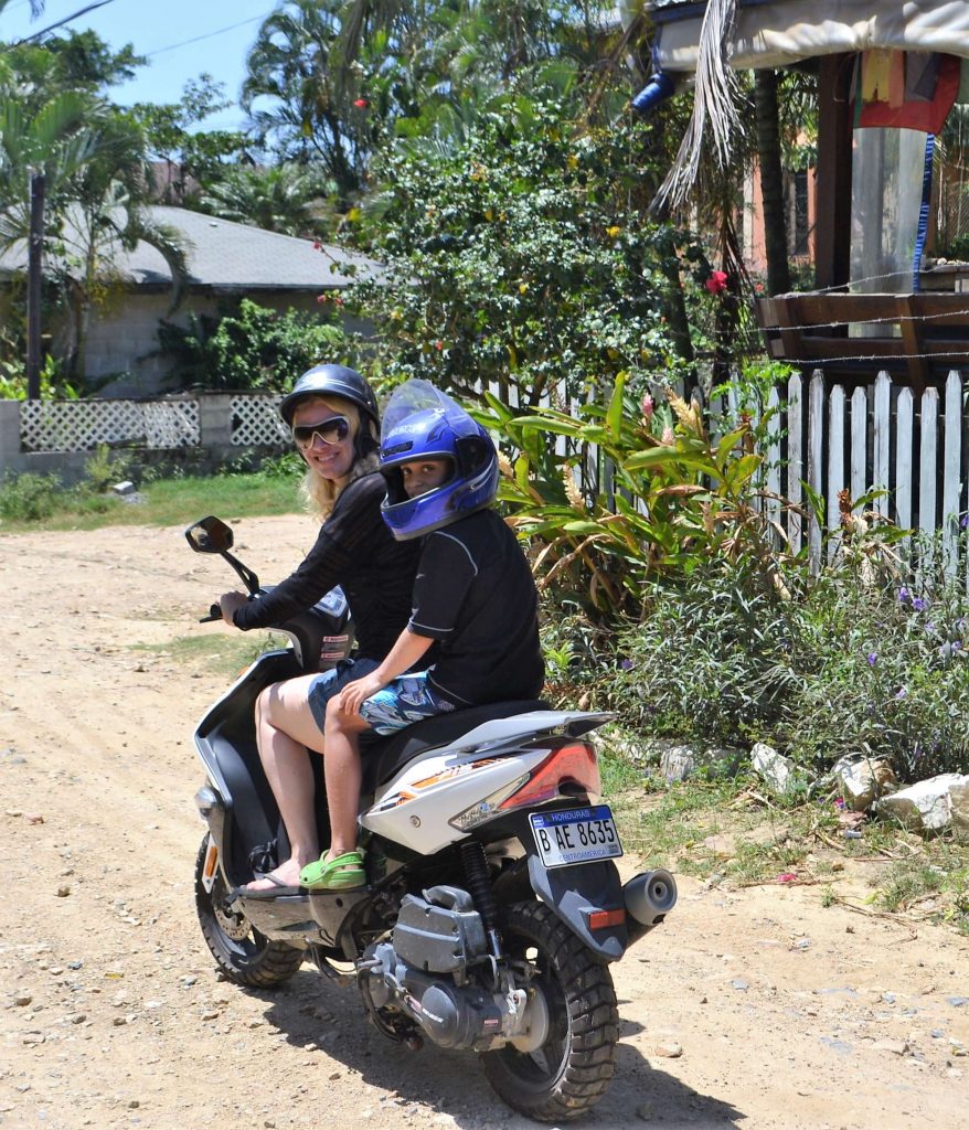 mom and kid on a scooter in roatan