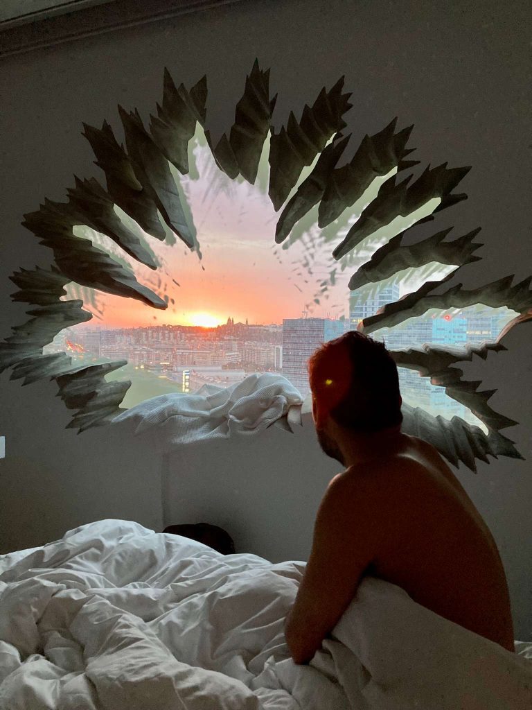 man in a bed looking through a window at renaissance hotel barcelona