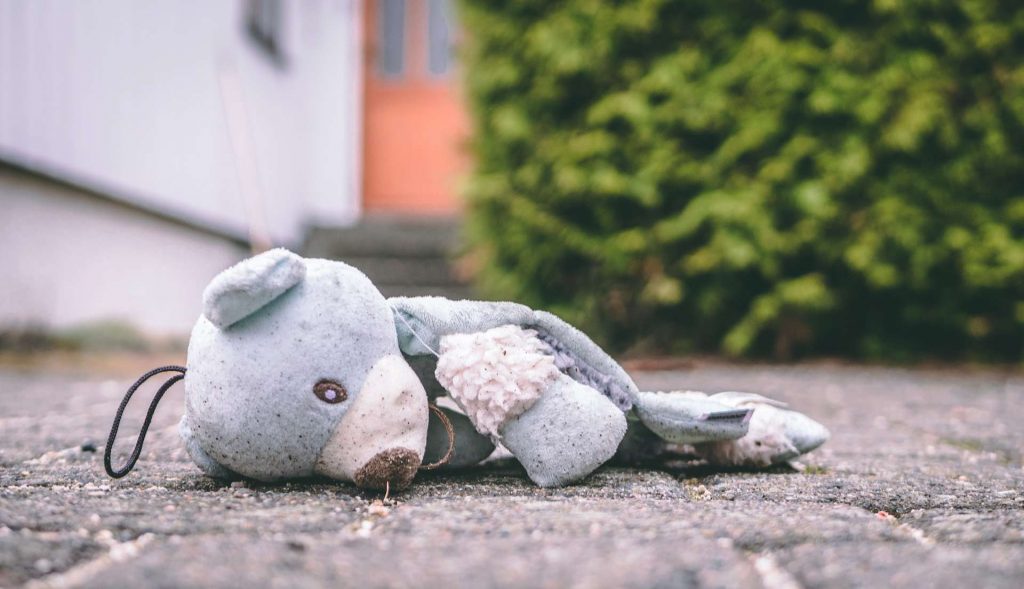 dirt bear plush toy in pavement