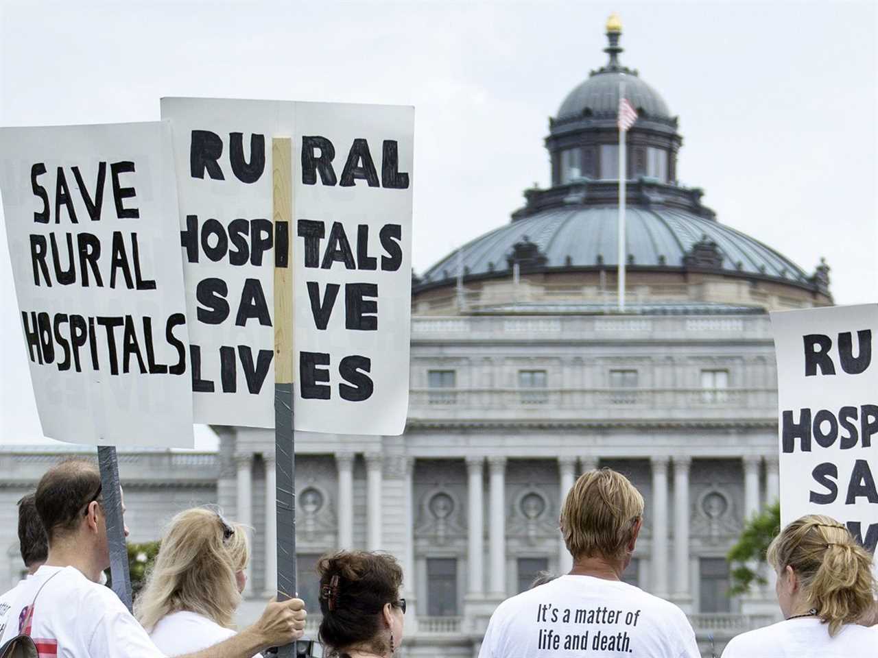 Protesters carry signs that read “Save rural hospitals” and “Rural hospitals save lives.”