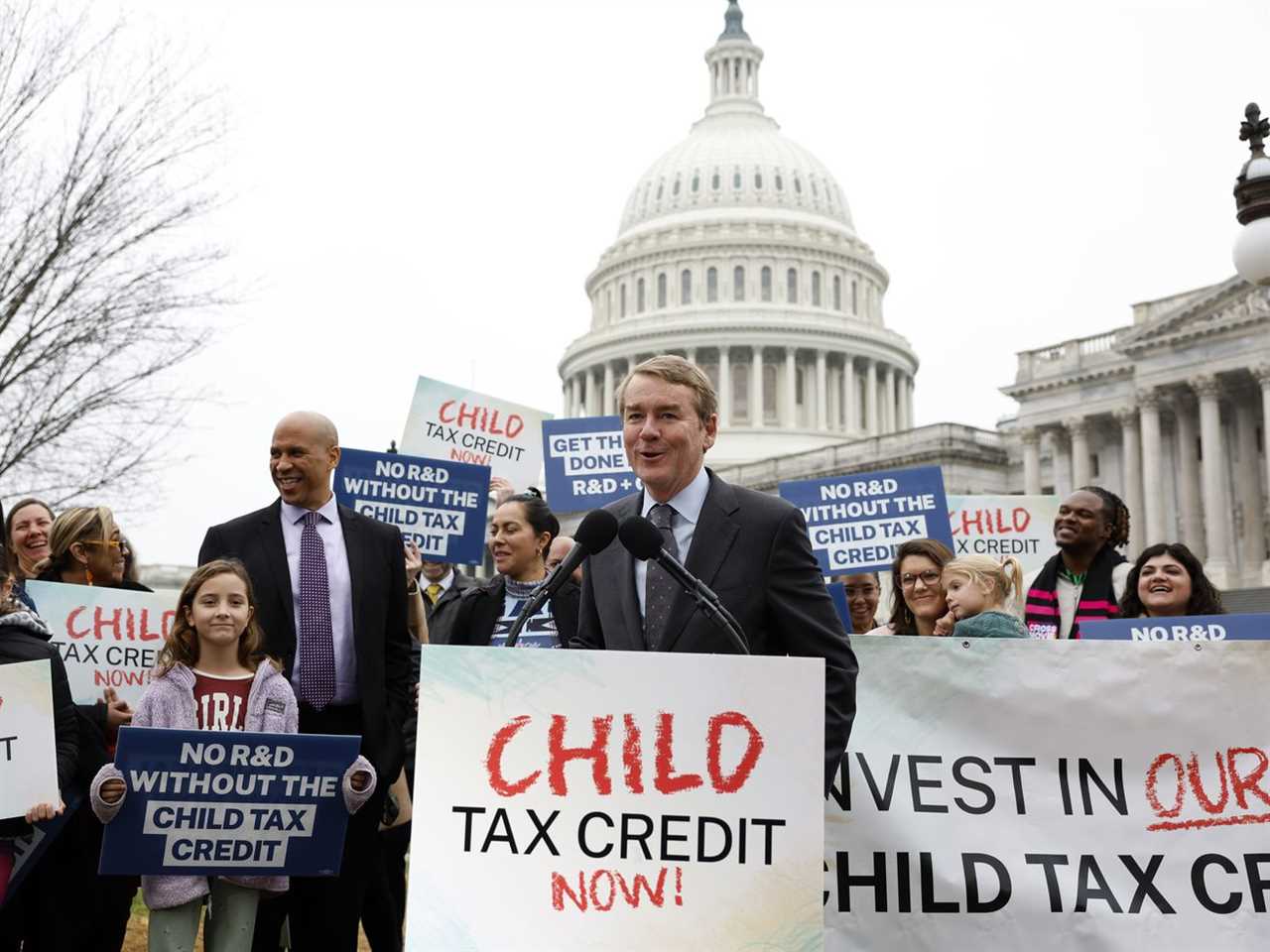 People gather outside the Capitol building holding signs that read “Child tax credit now!” and “No R&amp;D without the child tax credit.”