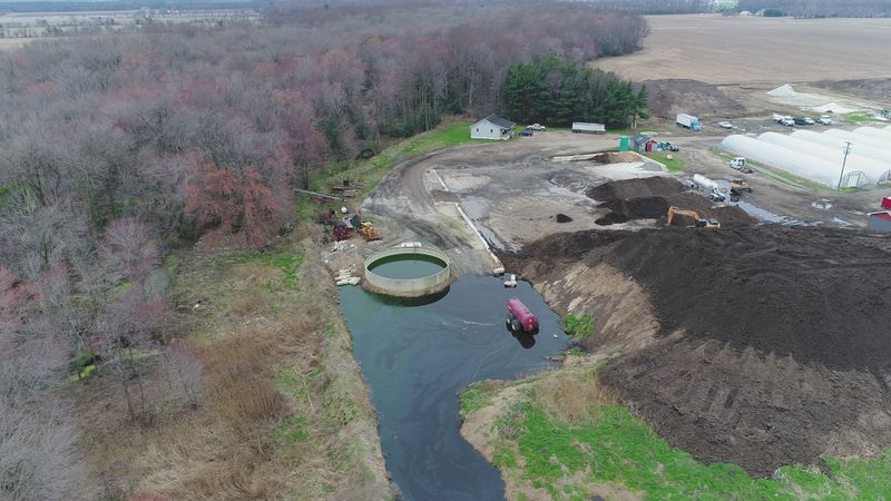 An aerial photo showing a huge mound of chicken waste, and a pond of liquid waste next to it.