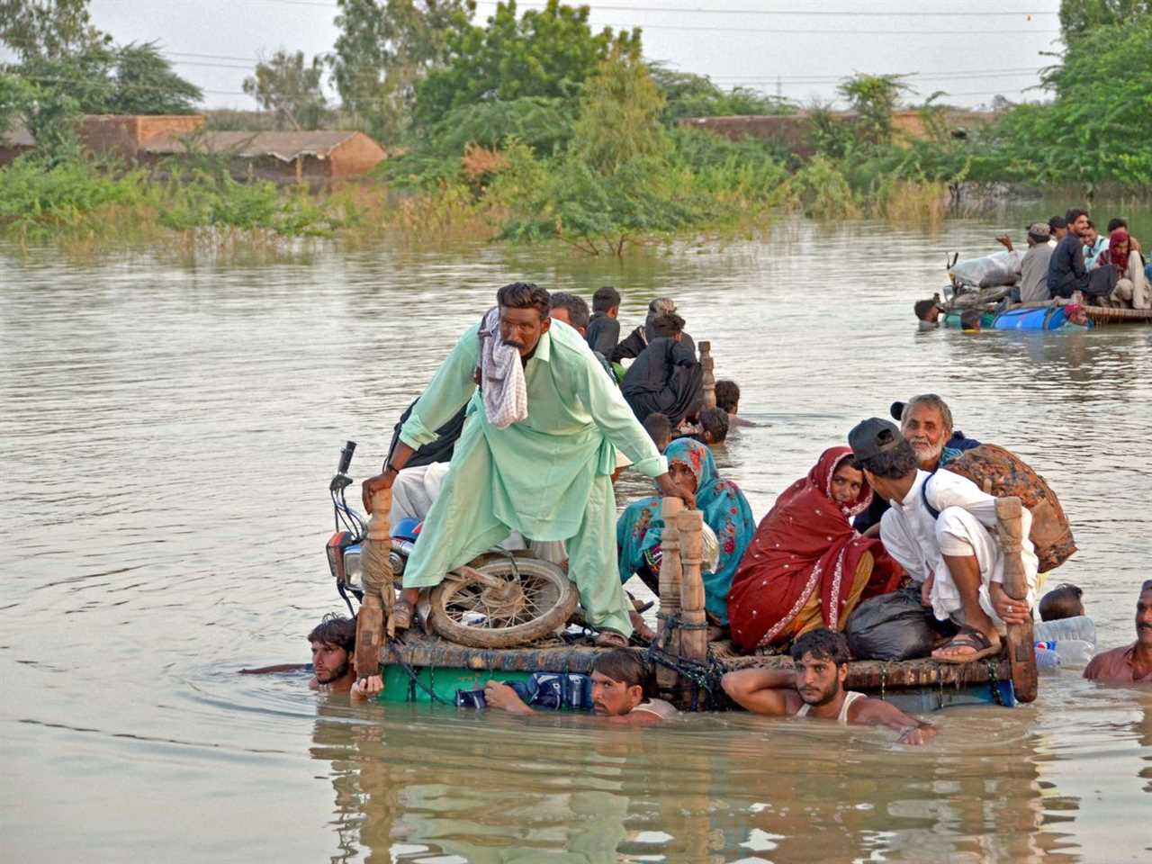 Internally displaced people wade through floodwaters after heavy monsoon rains in Pakistan’s Balochistan province on September 8, 2022.