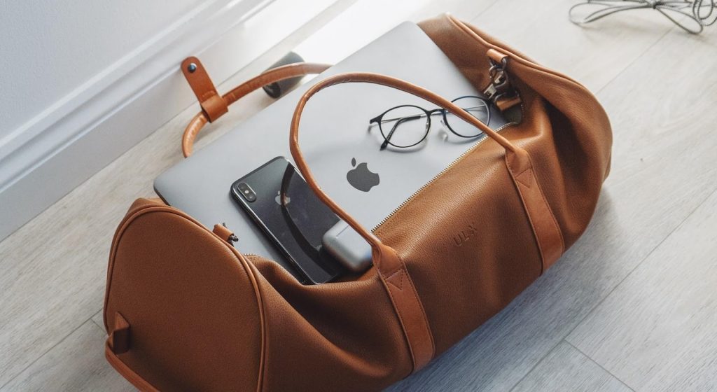 brown bag on the floor with a laptop, smartphone and glasses