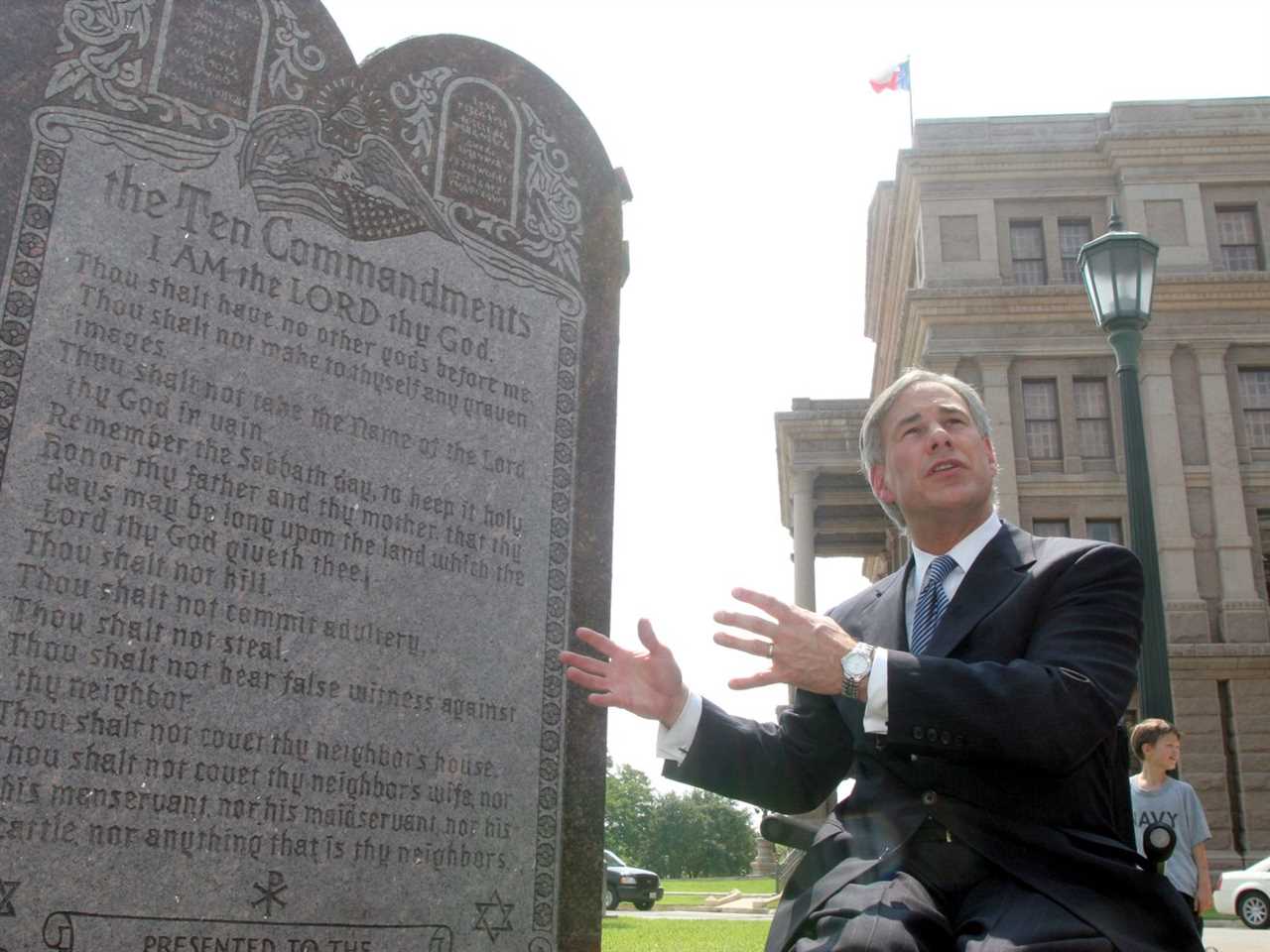 Greg Abbott stands in front of a stone monument displaying the Ten Commandments.