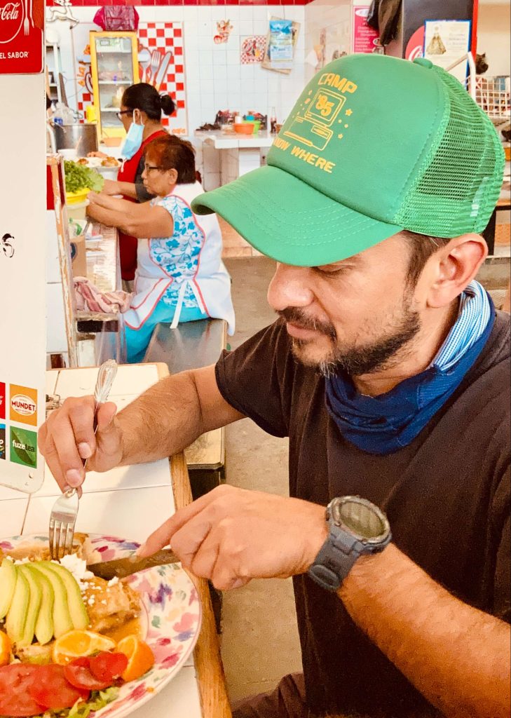 man eating oaxacan food in a market