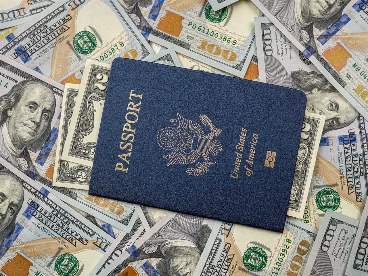 A US passport on a pile of $100 bills.