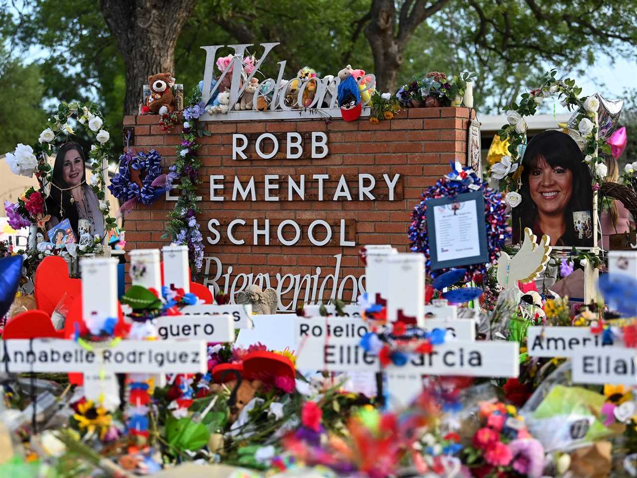 A sign for Robb Elementary School surrounded by objects, crosses, and photos. 