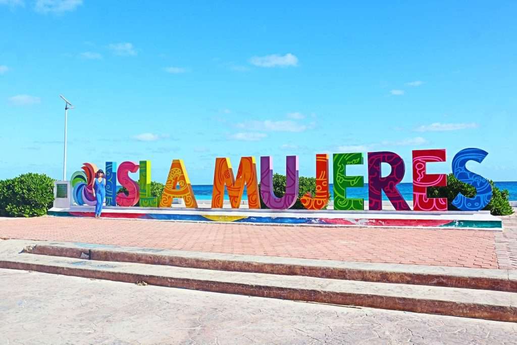 woman standing next to Isla Mujeres sign in Isla Mujeres, Mexico