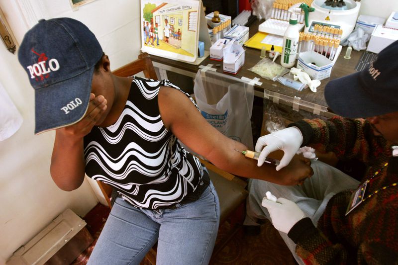 A women hides her eyes while receiving an injection in the arm.