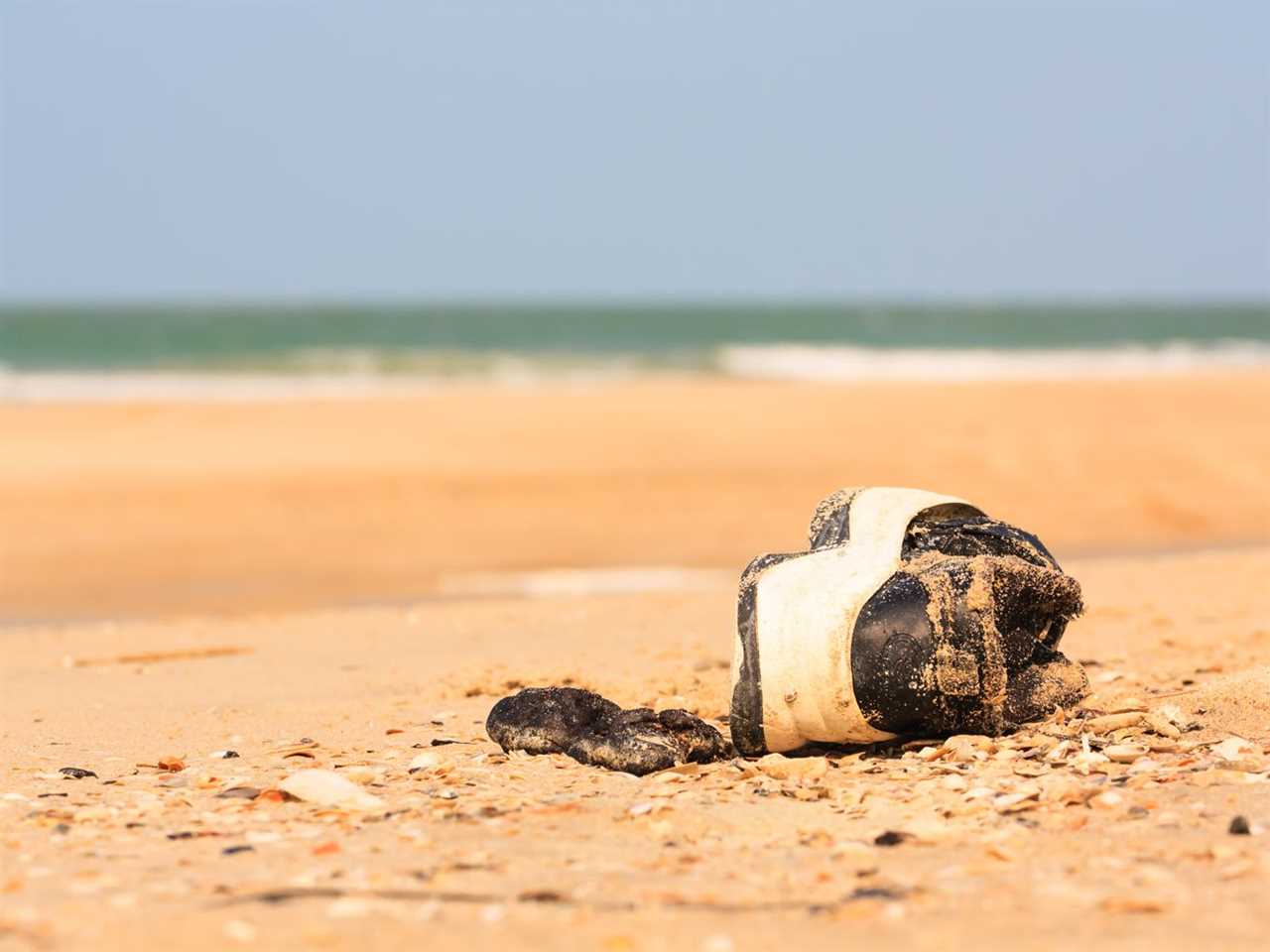 A shoe (just a shoe) on a beach.