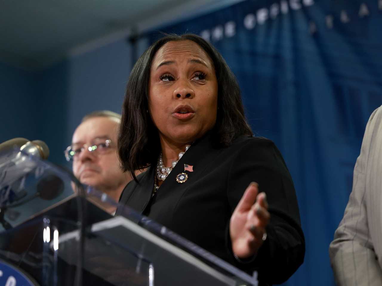 Fulton County DA Fani Willis gestures while speaking from the podium.