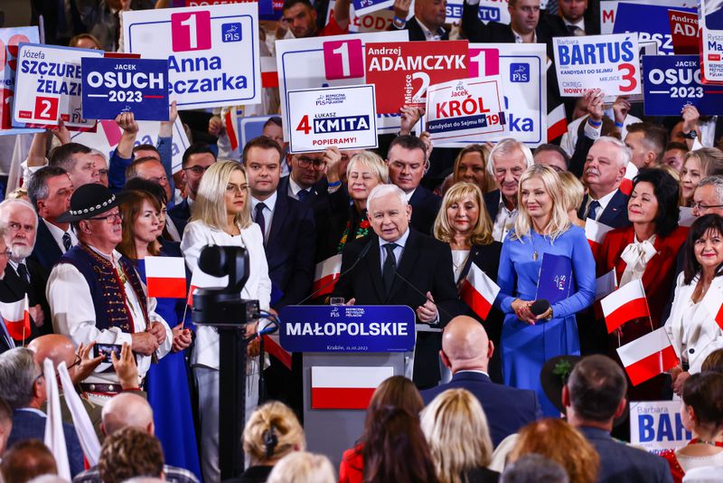 The candidate at a lectern surrounded by onlookers carrying signs and flags in support of him.