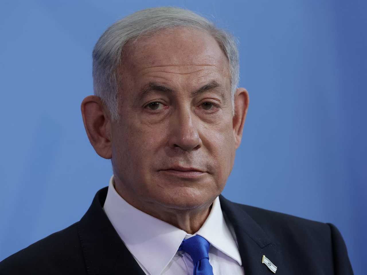 Benjamin Netanyahu, in a black suit, white shirt and blue tie, looks to the side during a media briefing in Berlin.