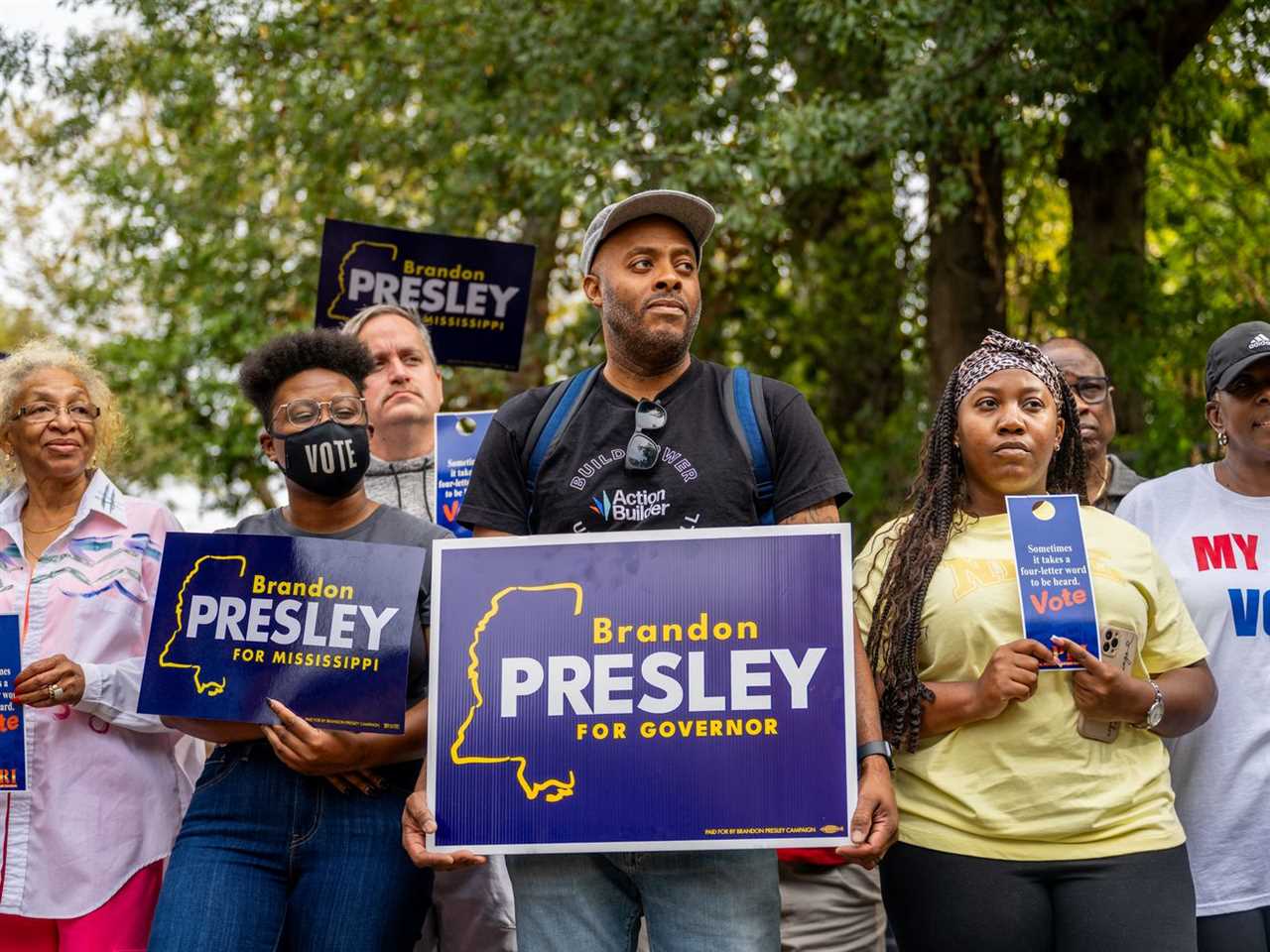 Supporters of candidate Brandon Presley stand outside and carry election signs.