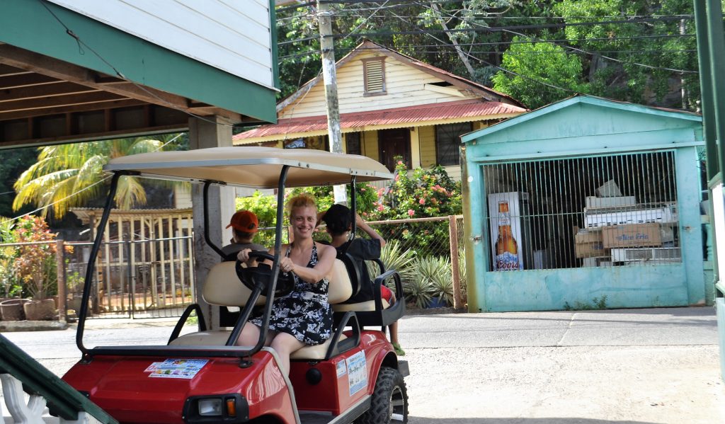 woman a golf car doing a tour of utila honduras