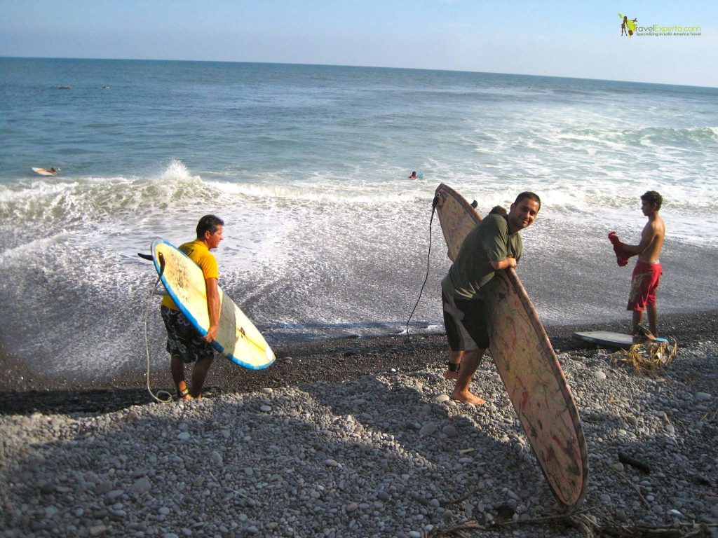people near the waves holding surfing tables in el tunco beach el salvador