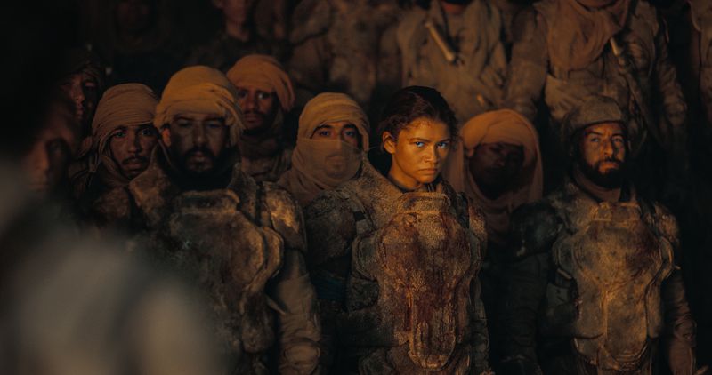 Zendaya glares at the camera while standing amid her fellow Fremen.