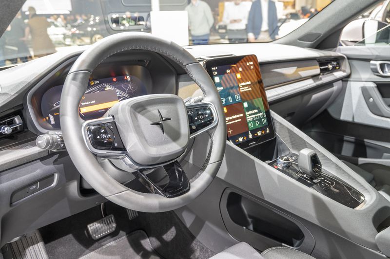  An interior view of the driver and front passenger section of a car, featuring a large screen dashboard and gray color scheme.