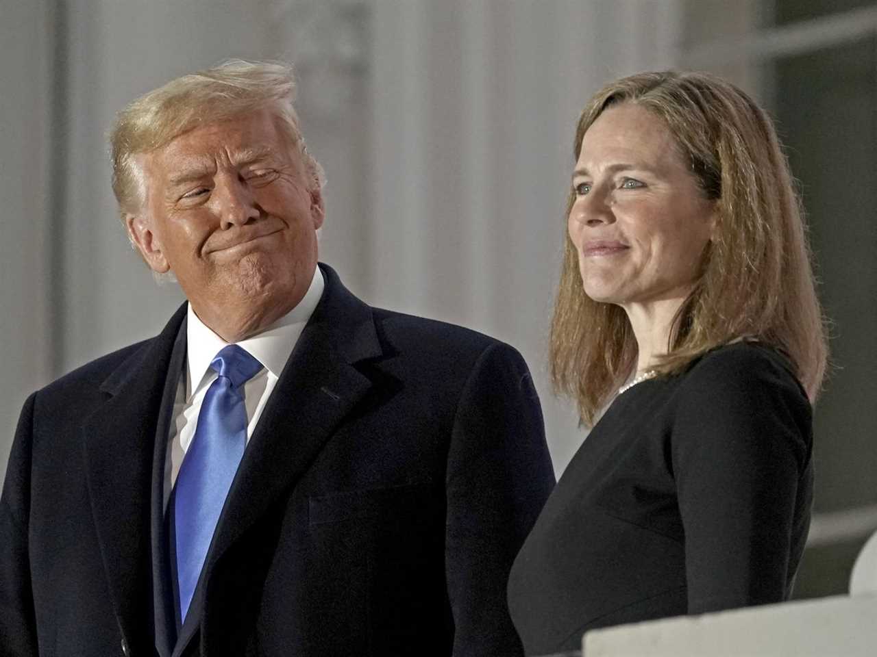 Trump grimaces in a smile at Amy Coney Barrett.